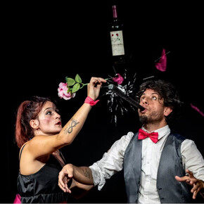 Nell'immagine si vedono i due attori mentre sollevano una bottiglia di vino, sorridendo felici insieme.