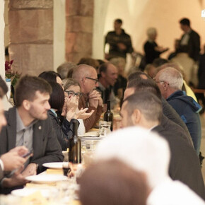 Long banquet tables under the portico of the cloister of the former Augustinian convent, filled with joyful people enjoying dinner and the company of friends.