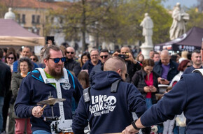 A GROUP OF DRUMMERS WITH DRUMS AND MANY SPECTATORS AROUND THEM WATCHING AND LISTENING