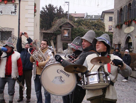 Nell'immagine si vedono i 5 componenti della banda intenti a suonare i loro strumenti in una piazza 