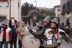 Nell'immagine si vedono i 5 componenti della banda intenti a suonare i loro strumenti in una piazza 