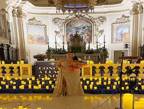 A WELL-DRESSED WOMAN AMIDST MANY CANDLES INSIDE A CHURCH