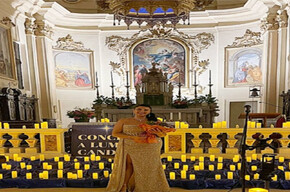 A WELL-DRESSED WOMAN AMIDST MANY CANDLES INSIDE A CHURCH