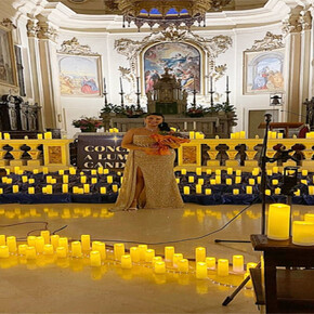 A WELL-DRESSED WOMAN AMIDST MANY CANDLES INSIDE A CHURCH