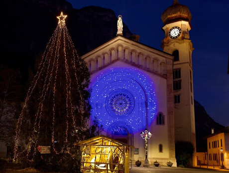 Piazza centrale del paese, con la Chiesa illumninata, l'albero di Natale e il presepe