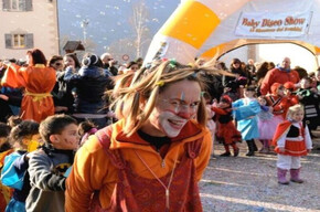 A friendly clown playing with children in the square with confetti and sparklers.