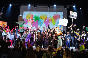 Nella foto sono presenti moltissime persone - adulti e bambini - vestiti in maschera mentre festeggiano il Carnevale al palacongressi di Andalo