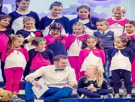 Children on stage, ready to sing a song.