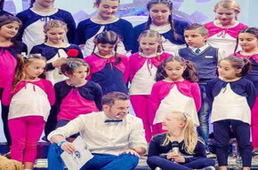 Children on stage, ready to sing a song.