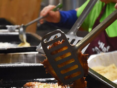 In the photo, people are cooking the typical potato dish ‘tortel di patate’, dipping the potato mixture into hot oil to fry it.